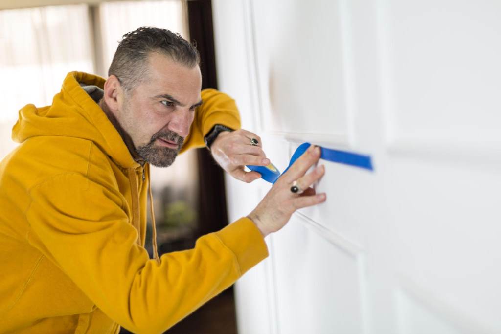 Applying painter’s tape for clean paint edges on interior wall