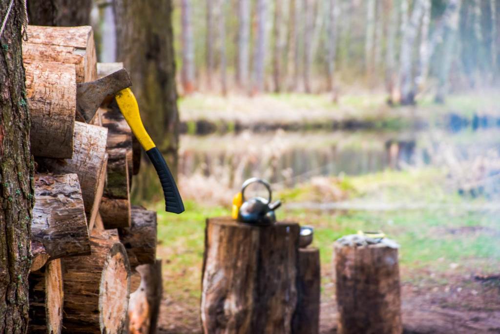 Camper using hatchet to chop firewood in forest campsite