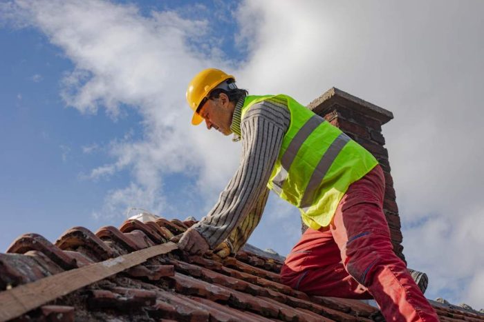 Construction worker repairing the roof of a building, work at height