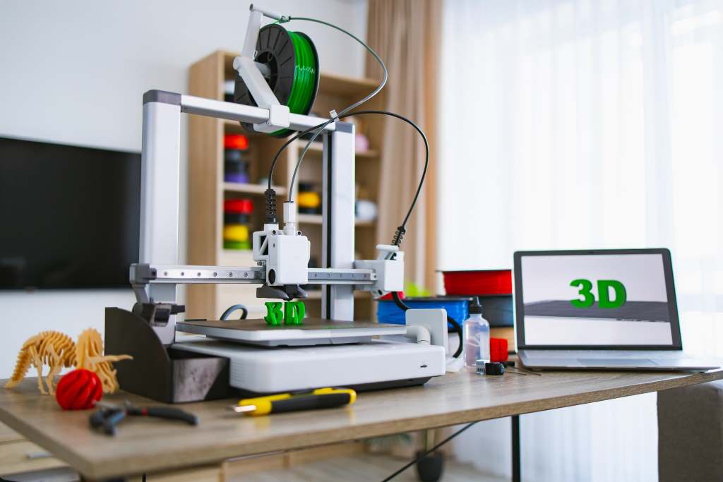 Desktop 3D printer creating a plastic model in a home workspace