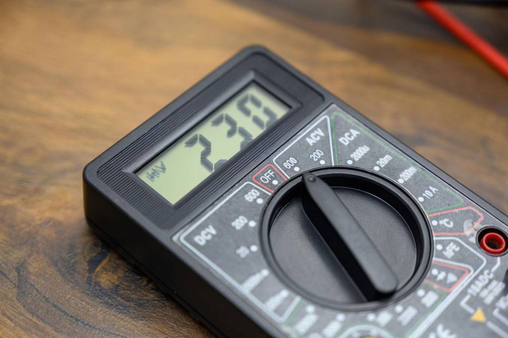 Digital multimeter measuring voltage on household outlet safely