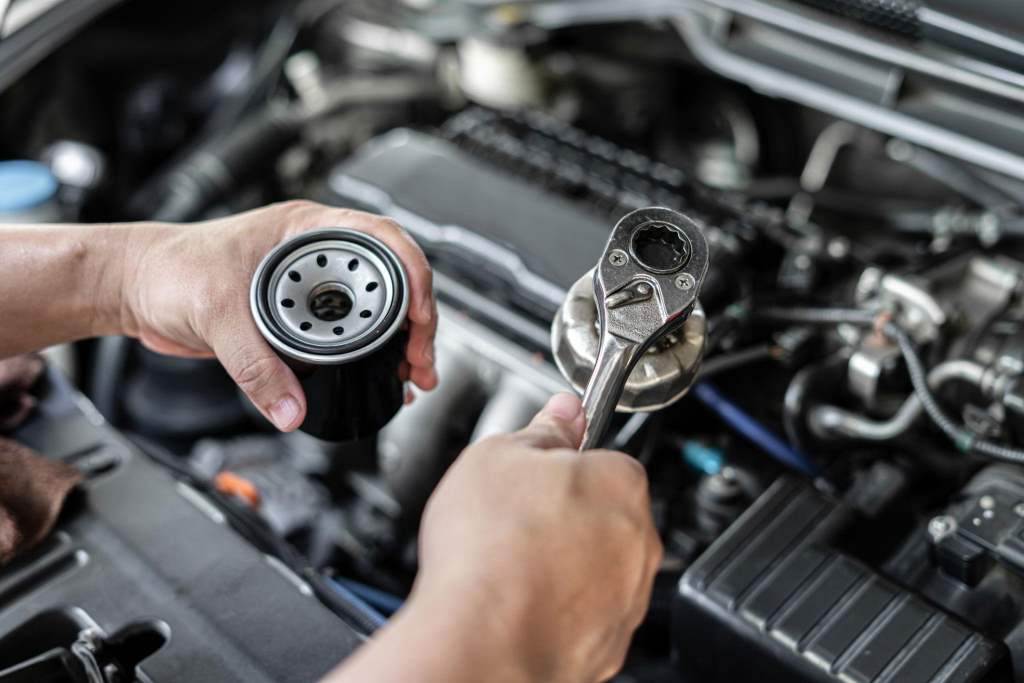 Mechanic using oil filter wrench to remove stuck oil filter from engine