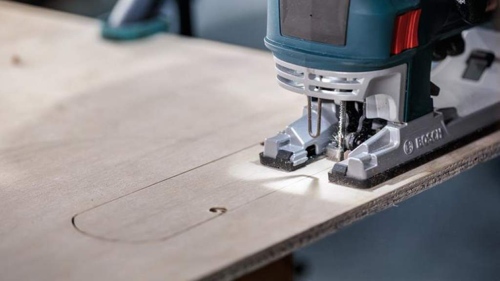 Person using a jigsaw to cut a straight line in wood