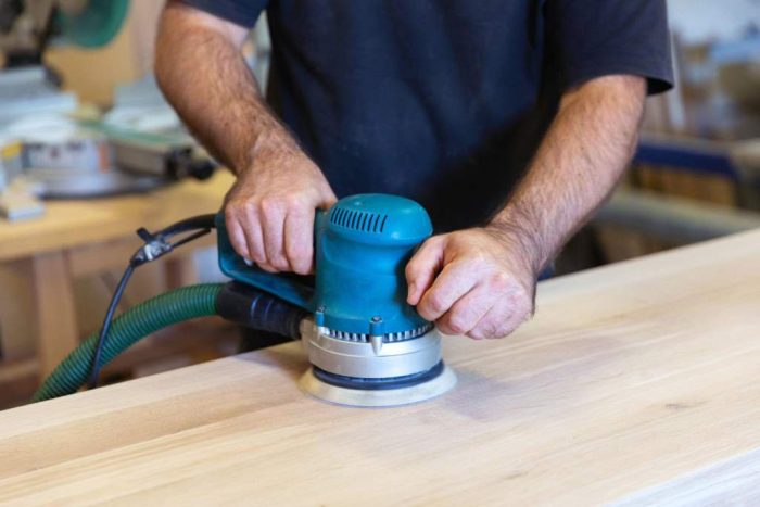 Sanding a wood surface with orbital sander