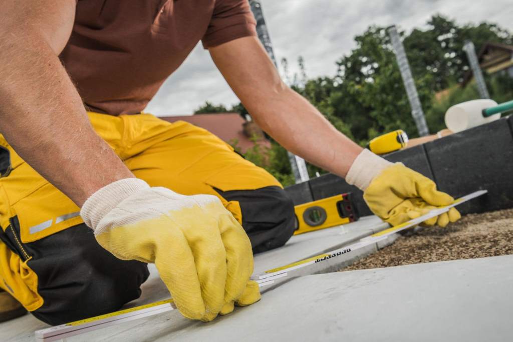Worker Measuring Material With a Tape Measure in a Construction Area During Daylight Hours