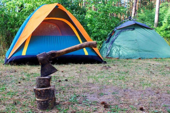 chopping wood with an ax the background of camping tents